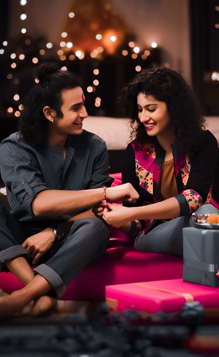 a man and woman sitting on a couch looking at an electronic device