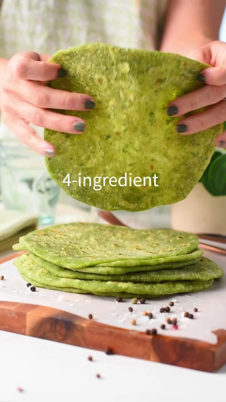 a woman is making green pancakes on a cutting board