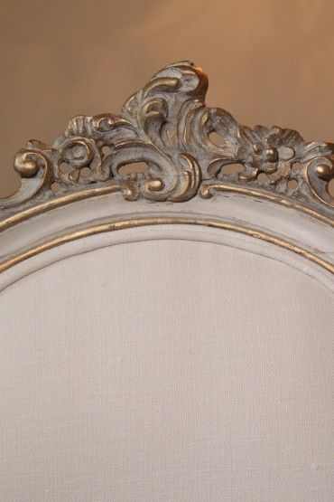 an ornately decorated bed frame with gold trimmings and white linen upholstered