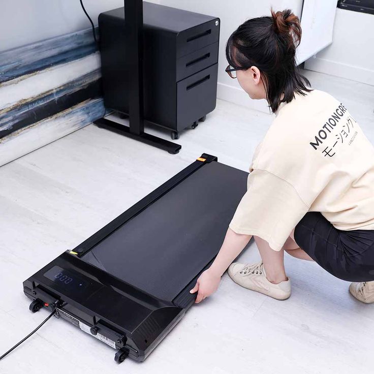 a woman kneeling down next to an electronic device