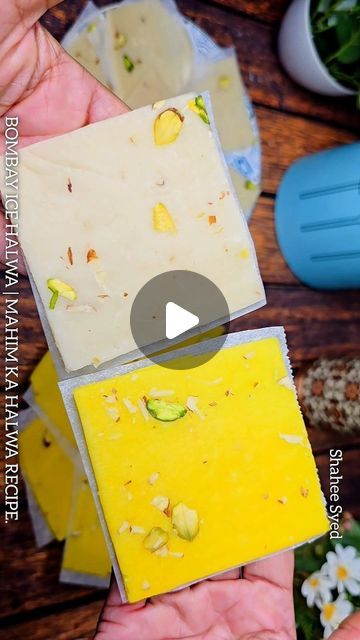 two hands holding pieces of yellow soap on top of each other with flowers in the background