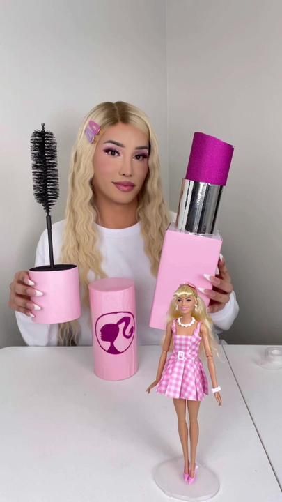 a barbie doll holding two hairbrushes in front of her face and some cups