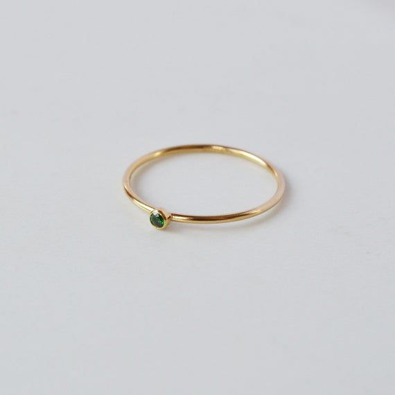 A super cute, tiny Emerald CZ stone ring gives you that barely there feel, with a touch of sparkle. Looks great alone or added to your daily stack! 14K Gold FilledBand is 1mm,  CZ stone is 2mmListing is for ONE RINGGold Filled has 100 times more gold than gold plated jewelry and will not chip or fade with wear! You can swim/shower, etc just like you would with solid gold. Gold filled wire is created by taking a sheet of 14 karat gold and bonding it through extreme heat and pressure to a core of Minimalist Open Ring For May Birthstone, Minimalist May Birthstone Open Ring, Minimalist Crystal Ring With May Birthstone, Minimalist May Birthstone Stackable Ring, Minimalist May Birthstone Promise Ring, Dainty Stackable Emerald Open Ring, Minimalist Birthstone Midi Rings For Everyday, Minimalist Stackable Emerald Open Ring, Adjustable Minimalist Emerald Ring For Everyday