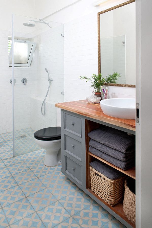 a bathroom with blue and white tile flooring, a wooden counter top and sink