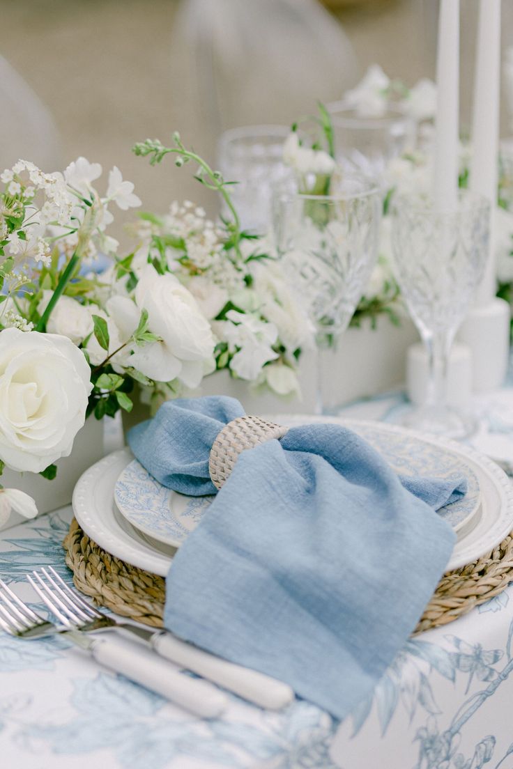 the table is set with white flowers and blue napkins