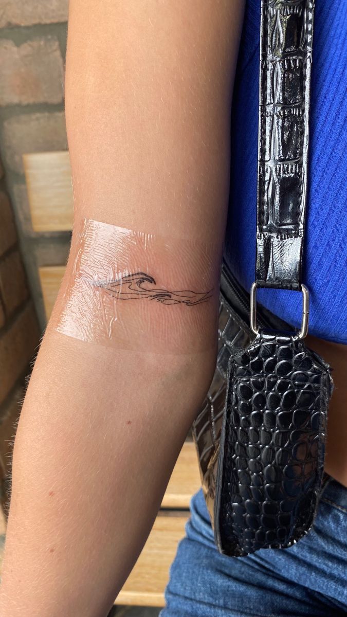 a woman's arm with a tattoo on it, and her wrist is covered in plastic