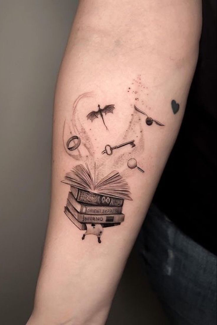 a person with a tattoo on their arm holding an open book and flying birds above it