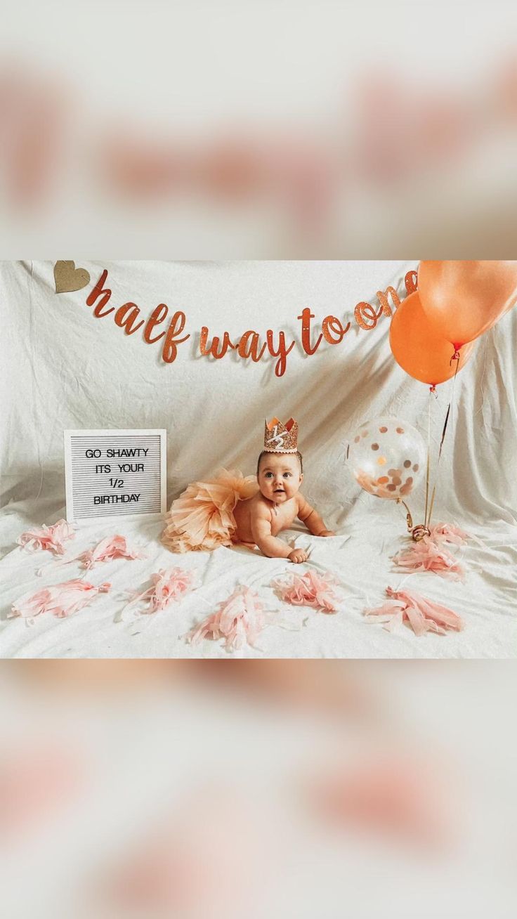 a baby is sitting on a bed with balloons and a sign that says happy birthday