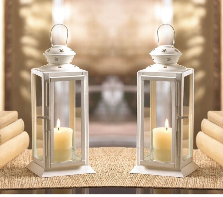 two white lanterns sitting on top of a table next to each other with candles in them