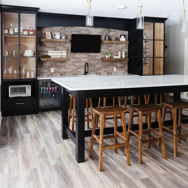 a kitchen with wooden floors and white counter tops next to a black refrigerator freezer