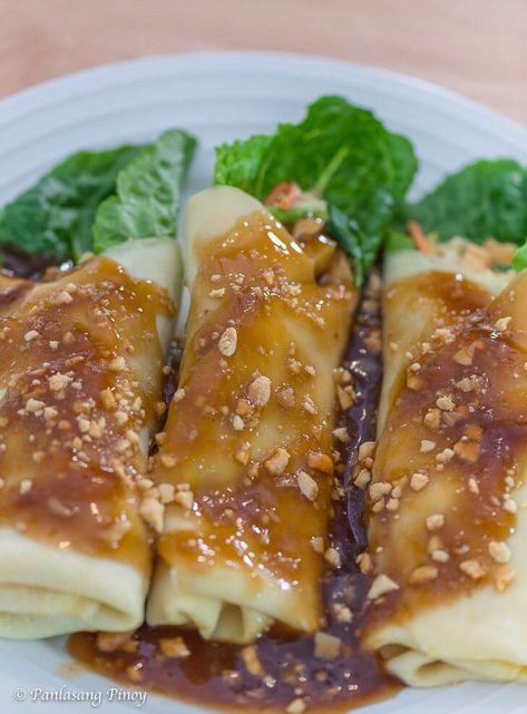 some dumplings with sauce and greens on a white plate