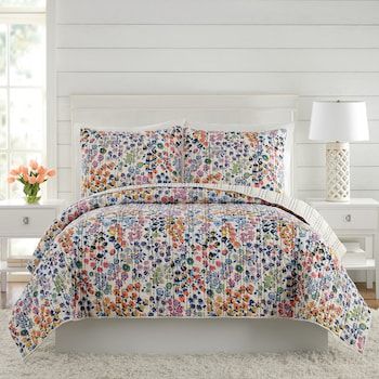 a white bed with a colorful comforter and pillows