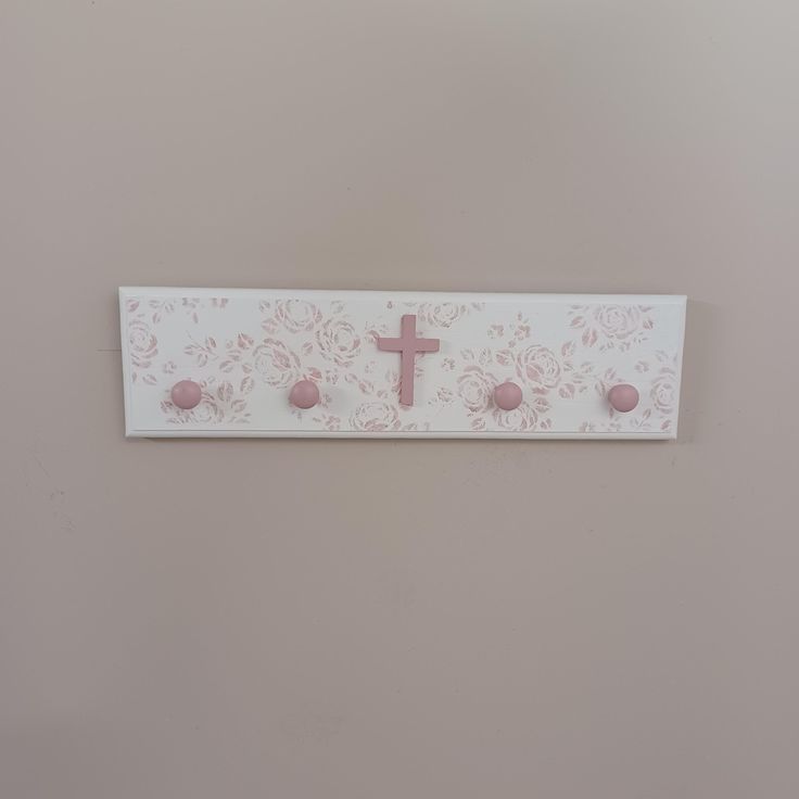 a cross is mounted on the wall with pink flowers