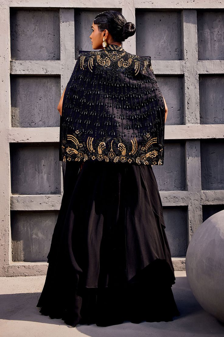 Black cape with floral embroidery and tassel detailing. Paired with pre-draped lehenga saree and embroidered blouse.
Components: 3
Pattern: Embroidered
Type Of Work: Floral
Neckline: Square
Sleeve Type: Cape sleeves
Fabric: Georgette, viscose satin organza
Color: Black
Other Details: 
Layered detailing
Cutout detailing
Gathered detailing
Occasion: Wedding - Aza Fashions Black Pre-draped Saree With Dupatta For Reception, Silk Sharara For Diwali Evening, Silk Sharara For Evening And Diwali, Black Bollywood Style Palazzo Set For Party, Black Bollywood Palazzo Set For Party, Black Pre-draped Saree With Zari Work, Traditional Silk Sets For Evening, Traditional Silk Evening Sets, Evening Palazzo Set With Resham Embroidery For Diwali