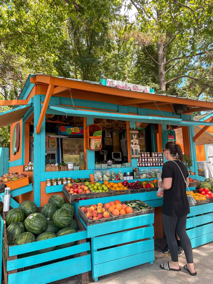 a woman standing in front of a fruit stand