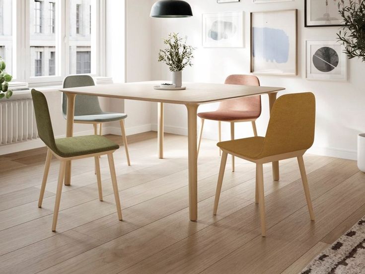 a dining room table with four chairs and a potted plant in the corner next to it