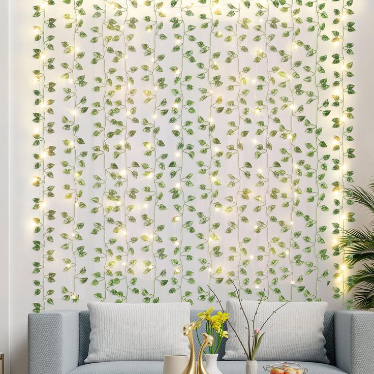 a living room with white walls and green leaves on the wall