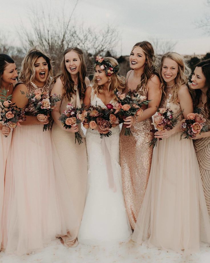 a group of women standing next to each other in front of a white wall with flowers on it