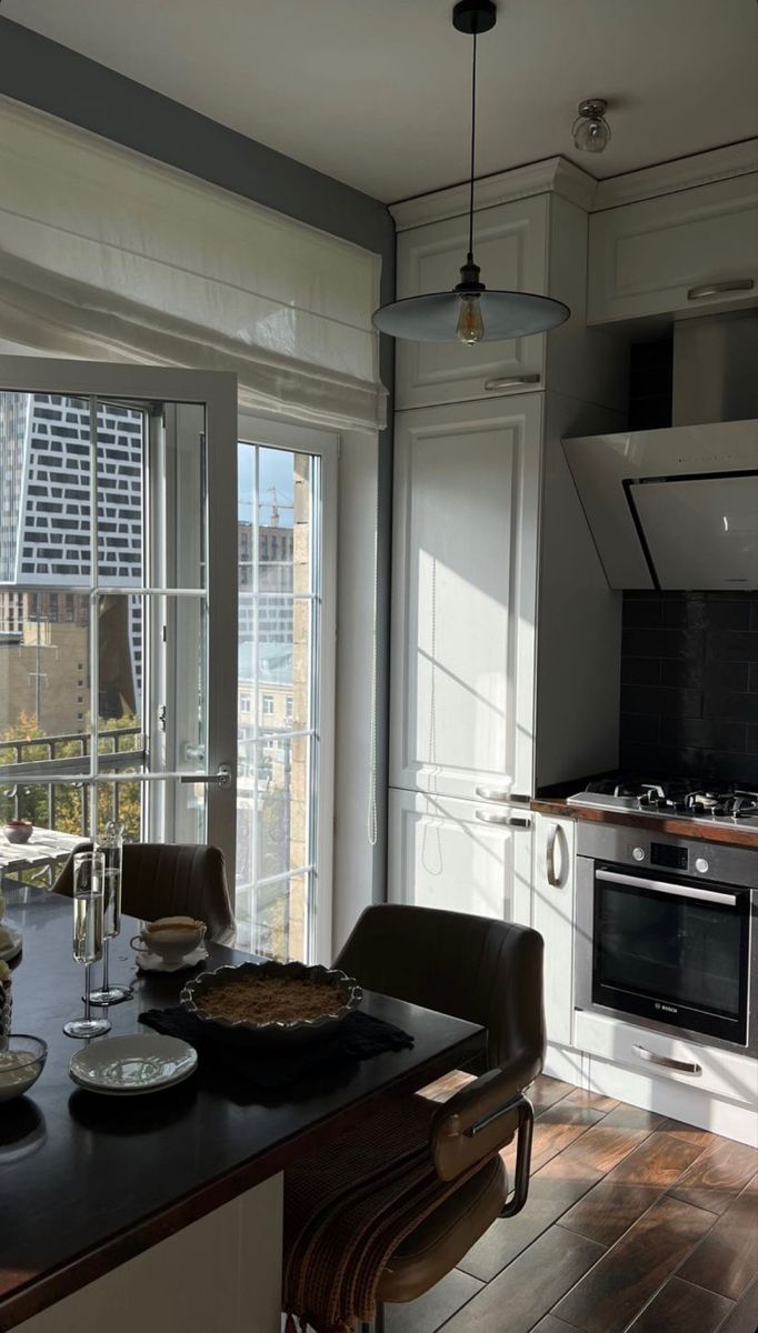 a kitchen with an oven, stove and table in it's center island next to a window