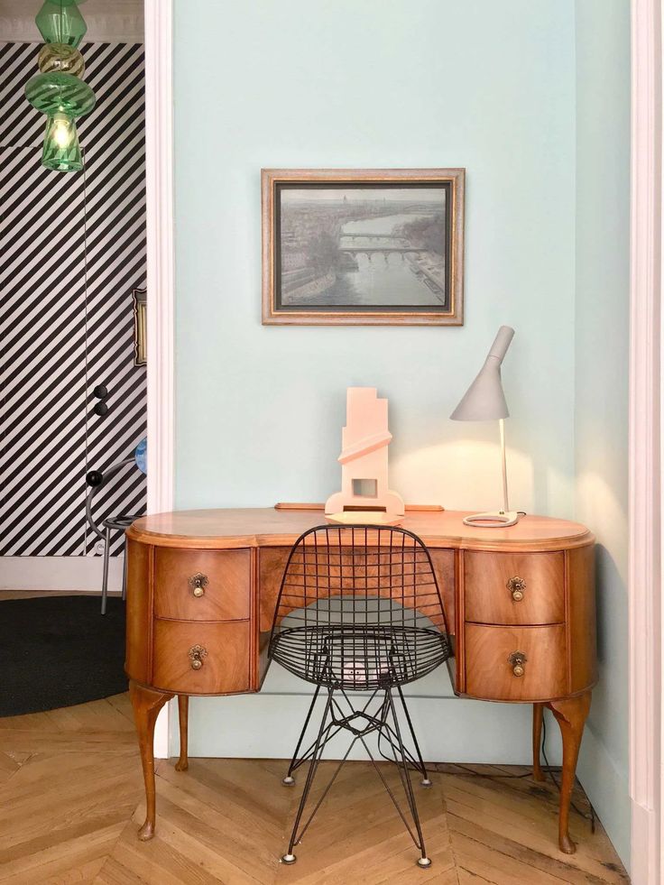 a desk with a chair next to it and a painting on the wall behind it