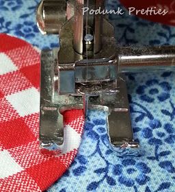 the sewing machine is on top of the fabric with red and white checkered tablecloth