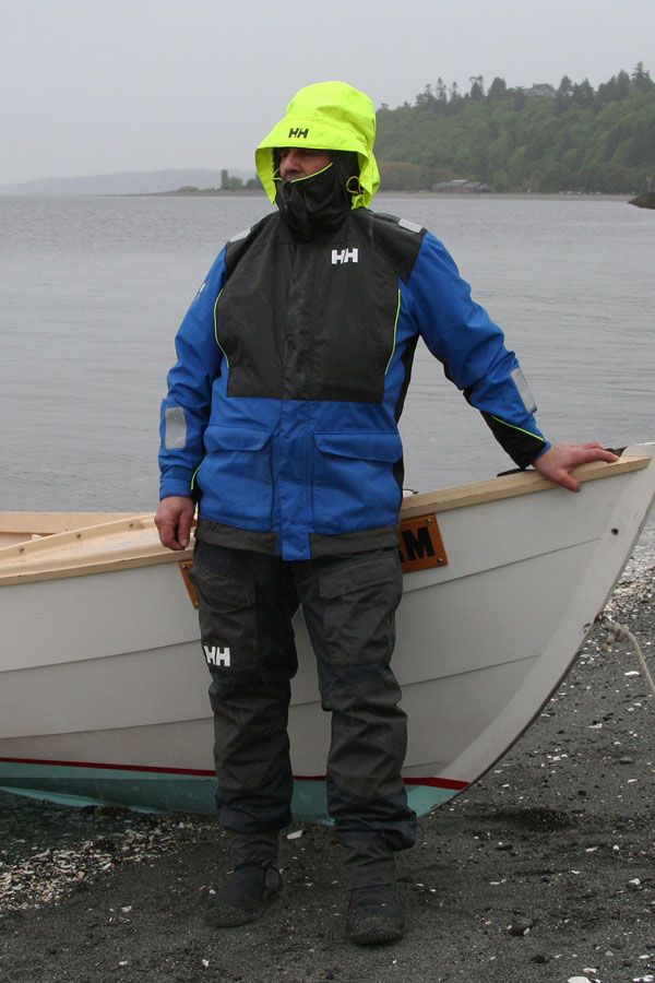 a man standing in front of a boat on the shore with his hands on his hips