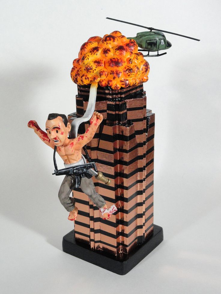 a statue of a man falling from a building with a helicopter flying over him and the fire coming out of his head