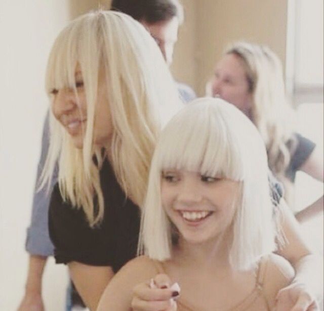 two women with blonde hair are smiling at the camera while another woman stands behind them