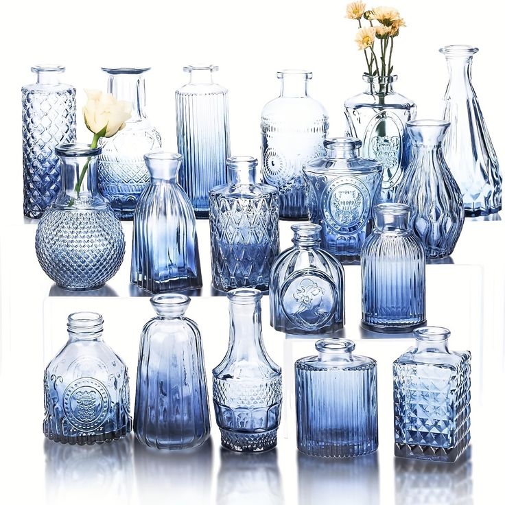 a collection of blue glass vases and bottles with flowers in the top right corner