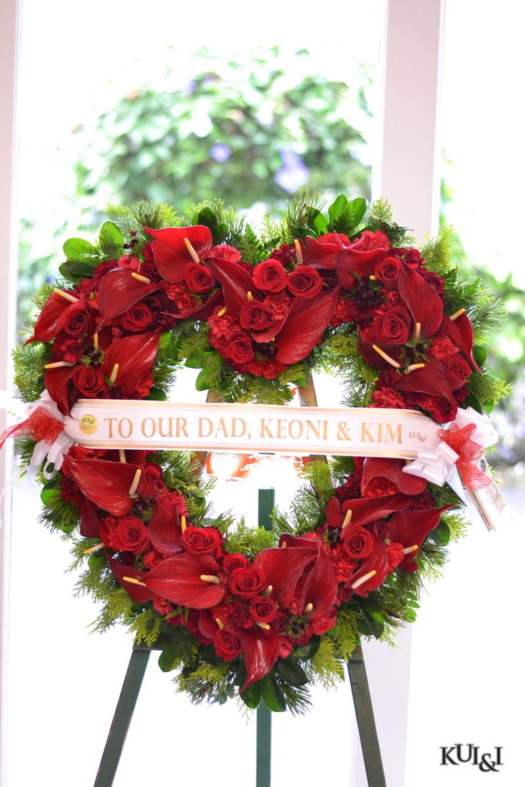 a heart shaped wreath with red flowers on it and a ribbon that says to our dad, knot & kim