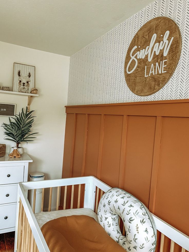 a baby's room with a crib, dresser and sign on the wall