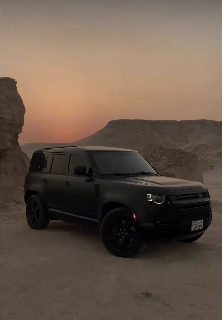 a black suv parked in the desert at sunset