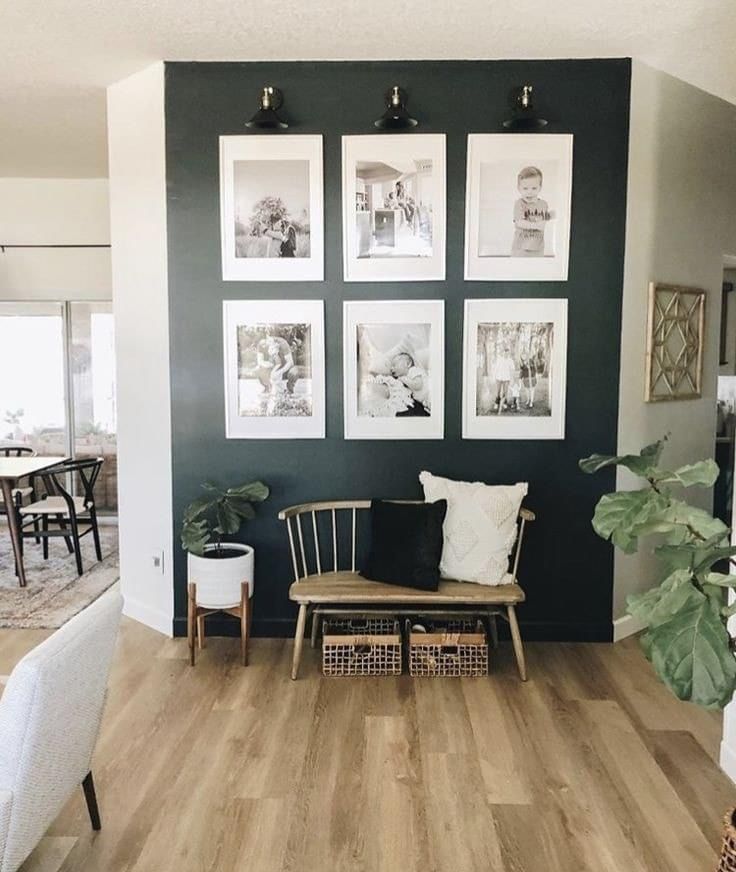 a living room with pictures hanging on the wall and chairs in front of the couch