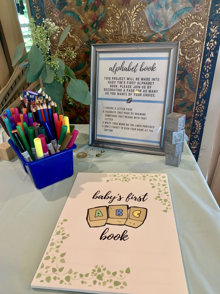 a baby's first book sits on a table with colored pencils in front of it