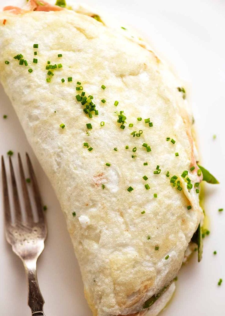 a white plate topped with an omelet and a fork