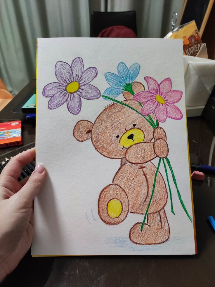 a drawing of a teddy bear with flowers in it's hand, on top of a table