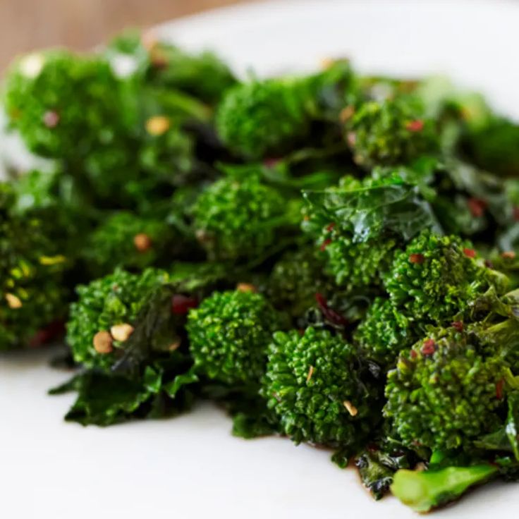 a white plate topped with broccoli on top of a wooden table