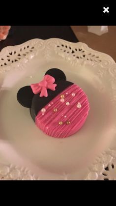 a pink and black mickey mouse cake on a white plate with doily around it