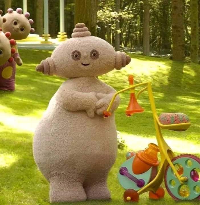 an inflatable character is standing next to a tricycle and other toys on the grass