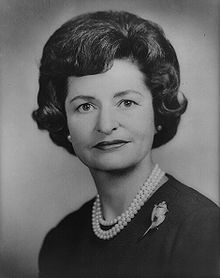 an old black and white photo of a woman with pearls on her necklace, looking to the side