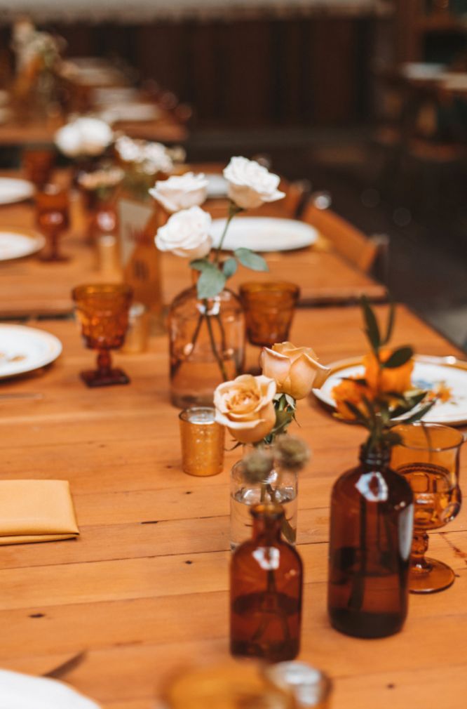 the table is set with several vases and place settings for guests to sit at