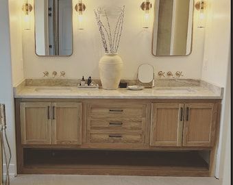 a bathroom with two sinks, mirrors and lights on the wall above them is shown