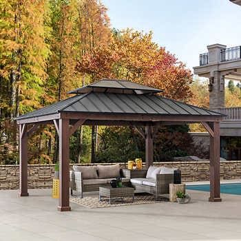 a gazebo sitting on top of a patio next to a swimming pool and trees