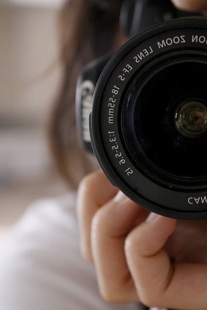 a close up of a person holding a camera with the lens in front of their face