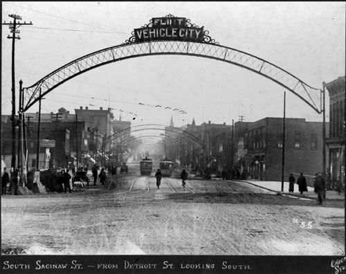 an old black and white photo of people walking under the arch that says, city vehicle