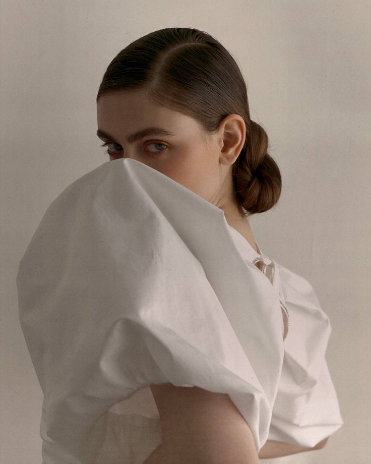 a woman wearing a white dress with her hair in a pony tail, wrapped around her shoulders