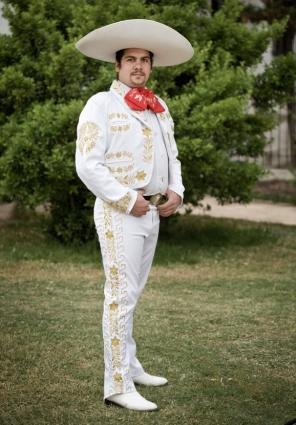 a man in a white suit and red tie wearing a sombrero with his hands on his hips