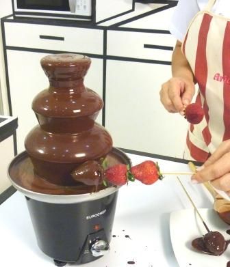 a chocolate fountain being used to make strawberries