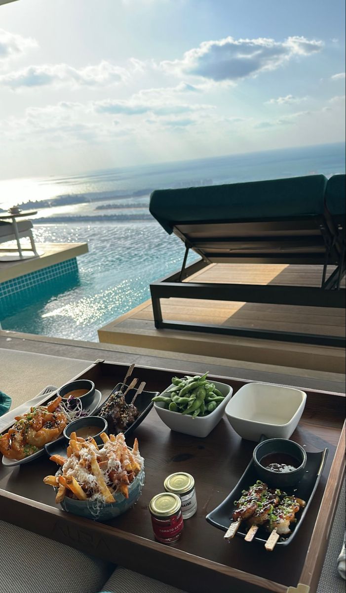 a tray with food sitting on top of a wooden table next to a swimming pool