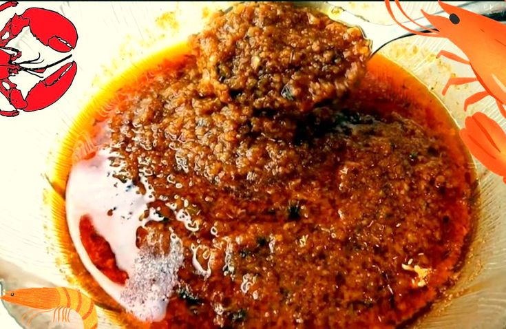 a bowl filled with meat and sauce sitting on top of a white plate next to an orange crab